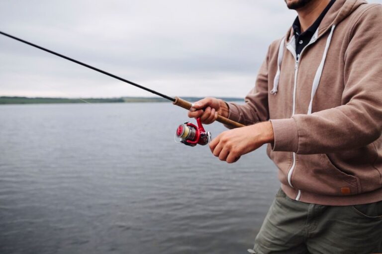 close-up-man-s-hand-holding-fishing-rod-near-lake